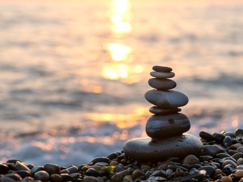 Stack of stones by water with sunset. 