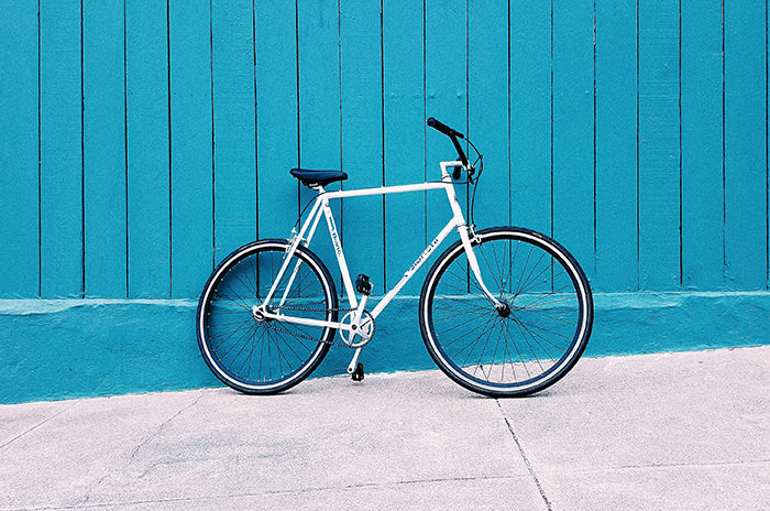 Bicycle leaning against a blue wall. 