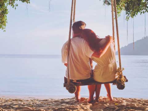 Couple sitting on swing looking at the water. 