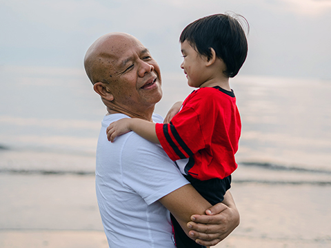 Elderly Asian man holding young Asian boy