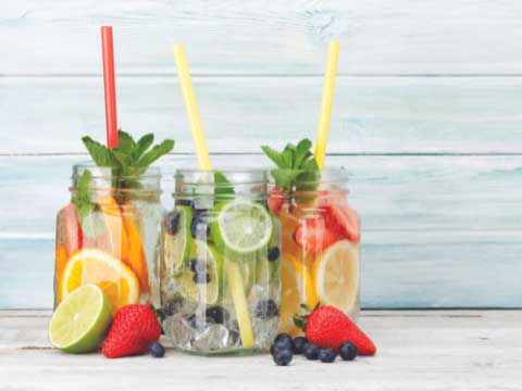Glasses filled with water and fruits with straws. 