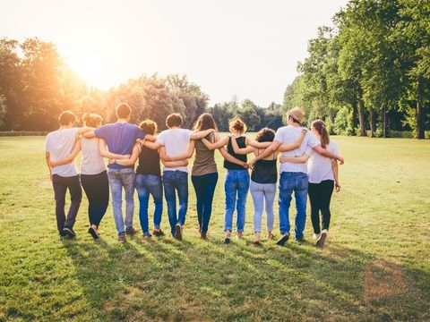 Group of people with arms wrapped around each other facing backwards.