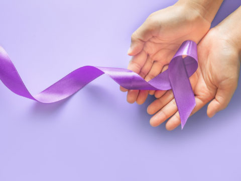 Hands holding testicular cancer awareness ribbon. 
