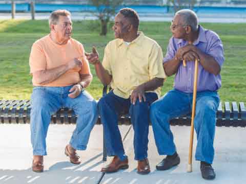 Three men sitting on a bench and talking