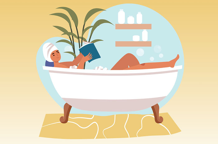 Woman reading book in bathtub.