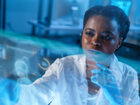 Black woman in lab looking at tech screen. 